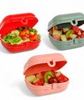Banana Easy Lock 600ml lunch boxes in red, sage green, and blush pink, filled with fruit salad and one with a fresh salad.
لانش بوكس سناكس و خضروات و فاكهه