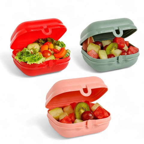Banana Easy Lock 600ml lunch boxes in red, sage green, and blush pink, filled with fruit salad and one with a fresh salad.
لانش بوكس سناكس و خضروات و فاكهه
