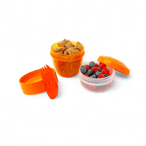 Banana Happy Cup 500 ml snack containers with 2-in-1 fork/spoon, one filled with cereal, one with berries.
شوكه و معلقه ، علبه سناكس ، كب زبادى