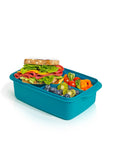 Banana 1.5L teal lunch box with removable splitter filled with a sandwich, blueberries, kiwi, cherry tomatoes, and carrots.